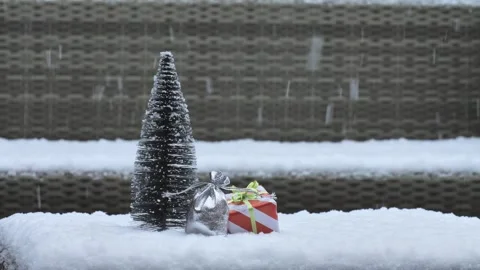 Snow blankets miniature tree and presents against wicker backdrop Stock Footage 344690222