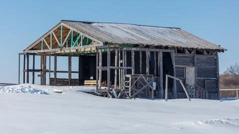 Snow blankets an old, half-constructed wooden barn Stock Photos