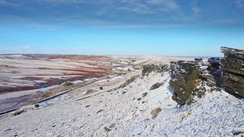 Snow blankets rocky cliffs under bright blue sky 스톡 동영상 347272523