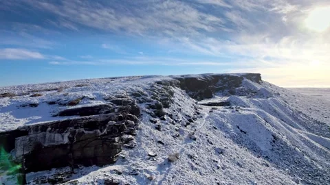 Snow blankets rugged cliff edges under clear, blue sky Vídeos de archivo 347273666