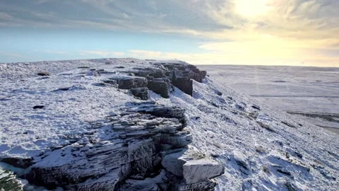 Snow blankets rugged stone cliffs under soft dawn sky 스톡 동영상 347273407