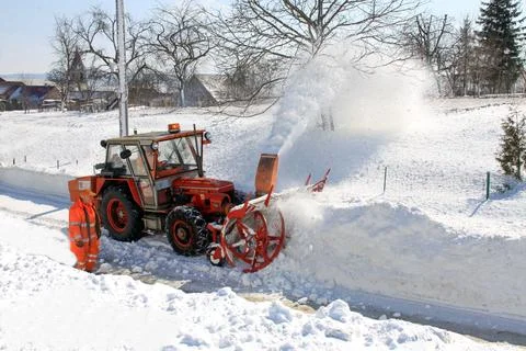 A snow blower breaks through a huge pile of snow Stock Photos