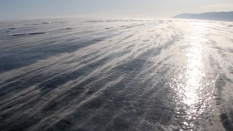 Snow blowing on ice from a strong wind on Lake Baikal in winter at sunset, Russi Stock Footage 126095533