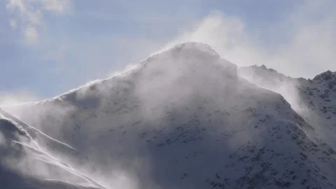 Snow blowing over the peak of a mountain in the North Caucasus, Russia, on a bri Stock Footage 320853408