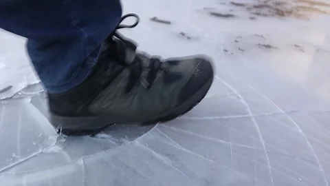 Snow boot crushes ice with force, sending the camera tumbling down Stock Footage 304884029