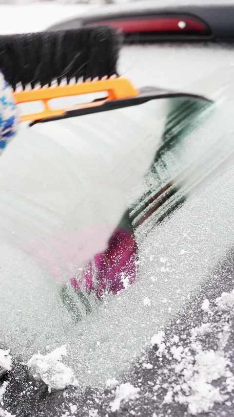 Snow brush and ice scraper clear thick frost from a car rear windshield Stock Footage 327889355