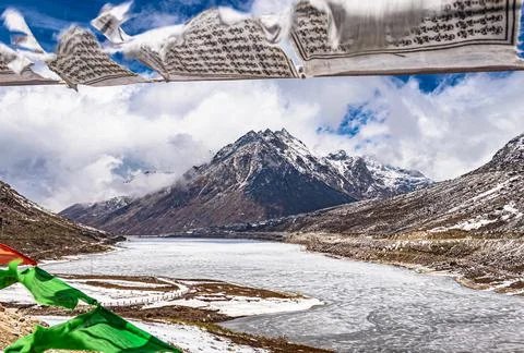 Snow cap mountain with dramatic sky through the blurred buddhism flags frame  스톡 사진