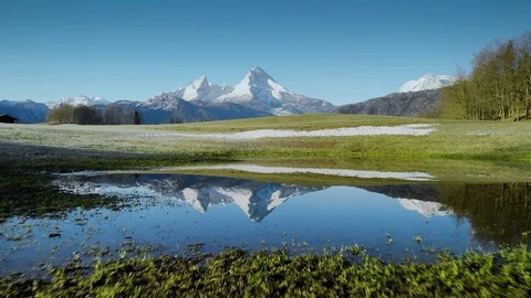 Snow-capped alpine peaks reflecting in crystal clear mountain lake in spring Stock Footage 108594394