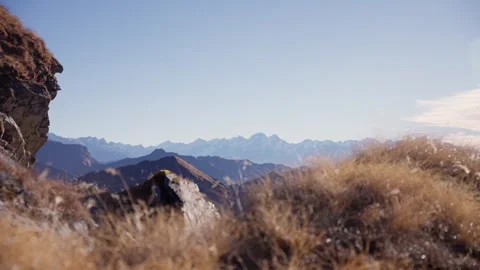 Snow capped distant Himalayan peaks framed by golden grass and rugged Vídeos de archivo 344178763