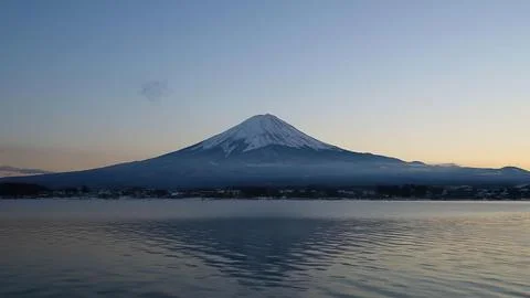 Snow-capped mount fuji over calm lake in japan at sunset Stock Photos