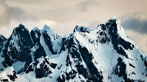 Snow-capped mountain peak with cloudy skies Stock Photos