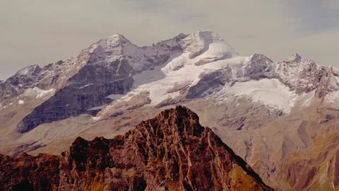 Snow-capped mountain peak towering over rugged rocky ridge Видео 345122433