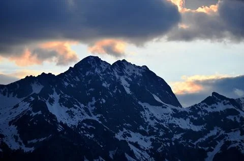 Snow-Capped Mountain Peak under Dramatic Sunset Clouds Stock Photos