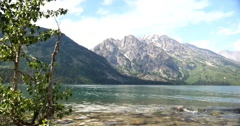 Snow-capped mountain peaks beside a peaceful alpine lake Stock Footage 341442350