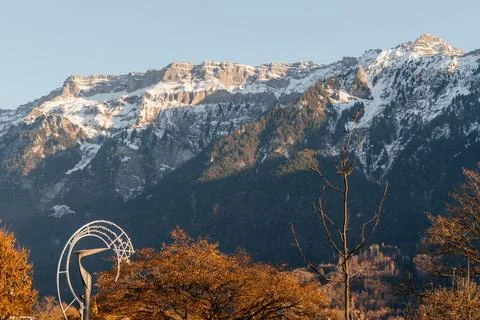 Snow capped mountain range rising above a peaceful rural landscape with green Stock Photos
