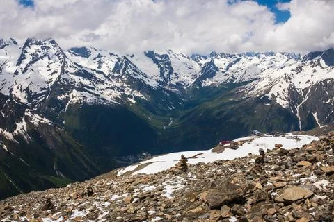 Snow-capped mountain range with rocky terrain and valley view under a partly Stock Photos