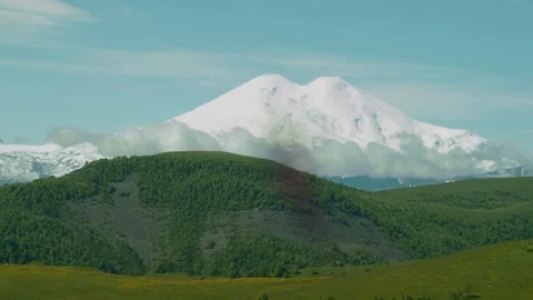 Snow-capped mountain range towers over lush green hills in a stunning natural Video stock 313108231