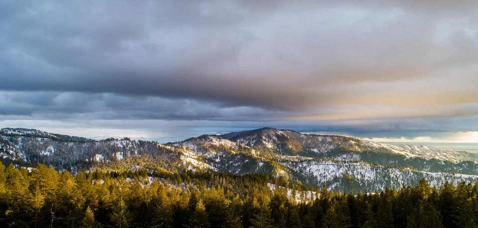Snow-Capped Mountain Range Under Dramatic Sky at Sunset Stock Photos