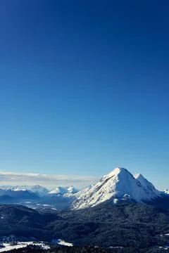 Snow-capped mountain range under bright blue sky in winter landscape near Stock Photos