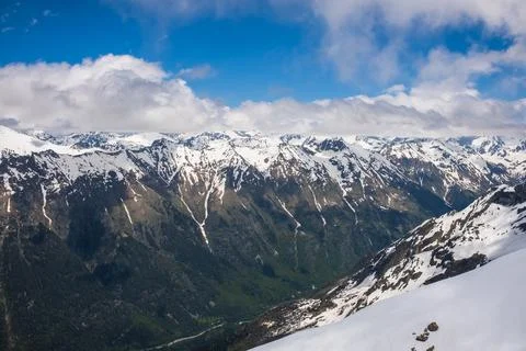 Snow-capped mountain range under a blue sky with scattered clouds, showcasing Stock Photos