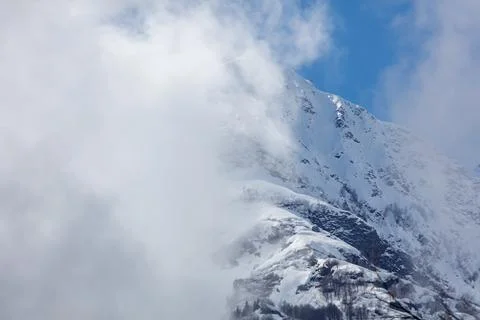 Snow-capped mountain rises above swirling clouds Fotos Stock