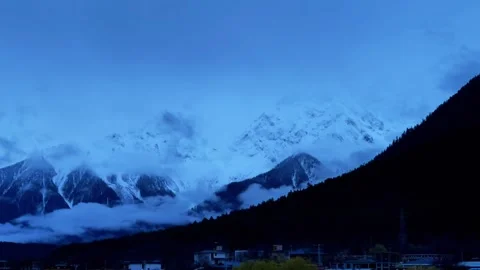 A snow - capped mountain surrounded by clouds and mist, time - lapse photography Stock Footage 312557580