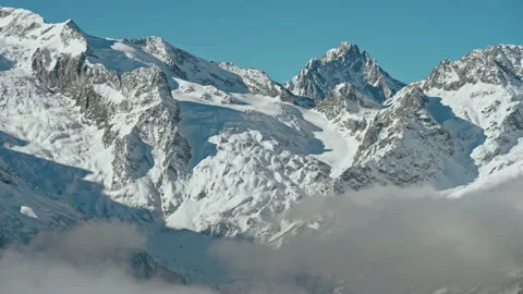 Snow capped mountains above clouds in a blue sky in sunny weather Stock Footage 138035708