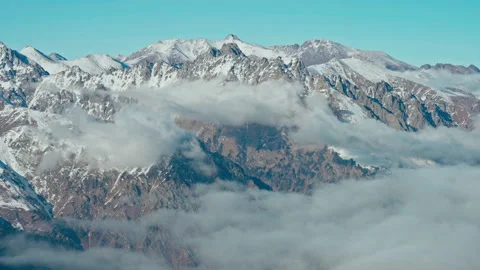 Snow capped mountains above clouds in a blue sky in sunny weather Stock Footage 138036309
