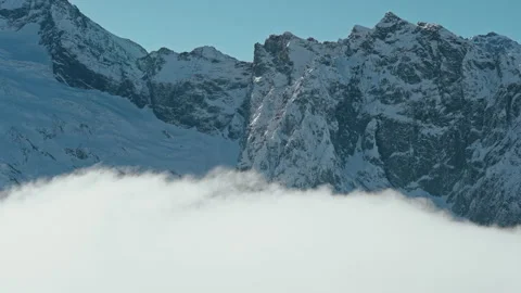 Snow capped mountains above clouds in a blue sky in sunny weather Stock Footage 138036390