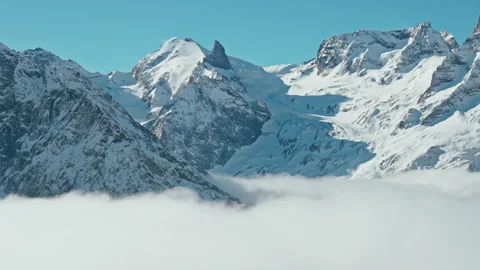 Snow capped mountains above clouds in a blue sky in sunny weather Stock Footage 138036726