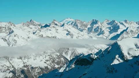 Snow capped mountains above clouds in a blue sky in sunny weather Stock Footage 138037006
