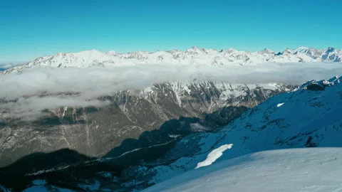 Snow capped mountains above clouds in a blue sky in sunny weather Stock Footage 138037808