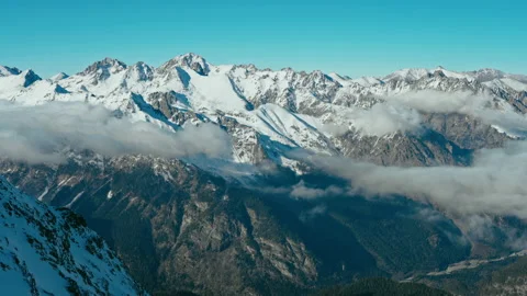 Snow capped mountains above clouds in a blue sky in sunny weather Stock Footage 138038259