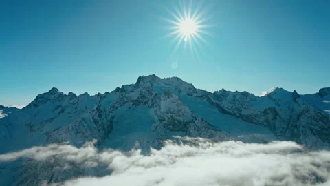 Snow capped mountains above clouds in a blue sky in sunny weather Stock Footage 138038613