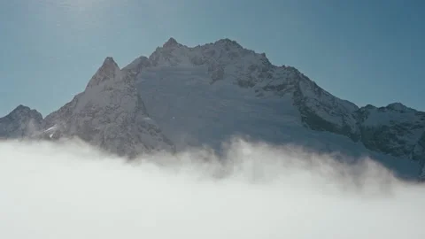 Snow capped mountains above clouds in a blue sky in sunny weather Stock Footage 138039371