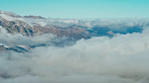 Snow capped mountains above clouds in a blue sky in sunny weather Stock Footage 138039873