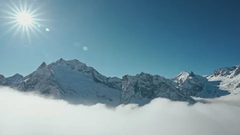 Snow capped mountains above clouds in a blue sky in sunny weather Stock Footage 138040332