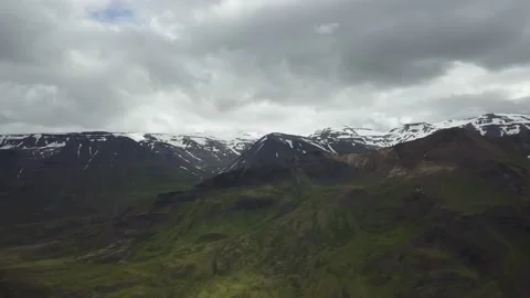 Snow capped mountains behind large mossy mountains Stockbeeldmateriaal 166854337