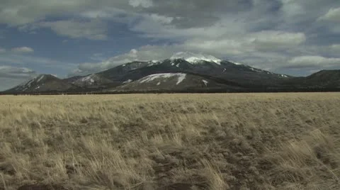 Snow Capped Mountains Between A Cloudy Sky and A Field Stock-Footage 19011004