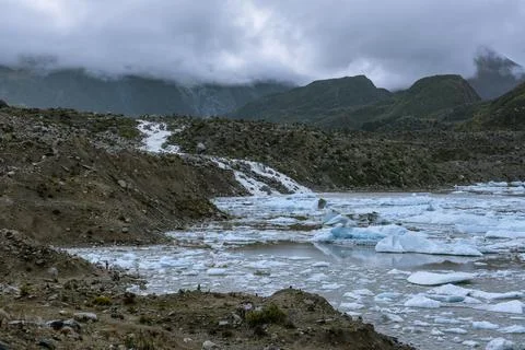 Snow-capped mountains in the clouds and glacial lakes at the foot of the moun Stock Photos