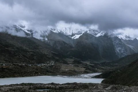 Snow-capped mountains in the clouds and glacial lakes at the foot of the moun Stock Photos
