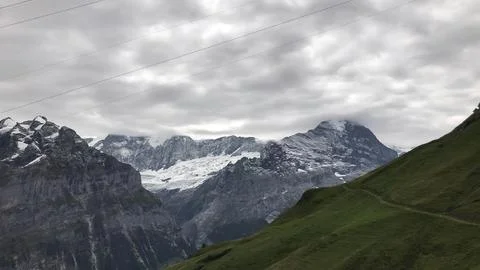 Snow-capped mountains with cloudy sky and green valleys Stock Photos