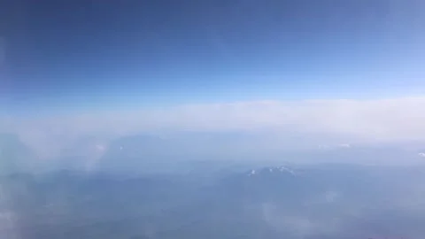 Snow capped mountains emerge through misty blue haze under clear sky as soft clo Stock Footage 310856598