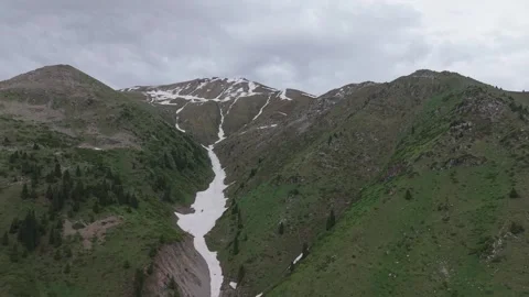 Snow-capped mountains with green valleys and flowing snowmelt river visible Stock Footage 336965068