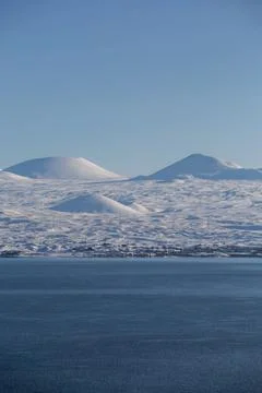 Snow capped mountains on lake sevan in clear weather at sunset Stock Photos