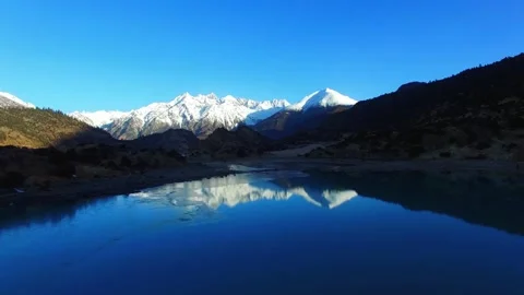 Snow capped mountains reflected in a pristine blue lake Stock Footage 311820154