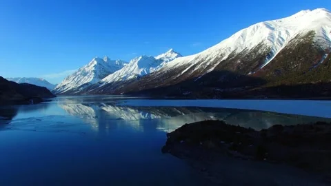 Snow capped mountains reflected in a serene blue lake Stock Footage 311816632
