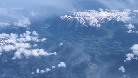 Snow-capped mountains seen through thin clouds from an airplane in flight. Stock Footage 303969098