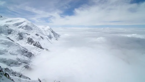 Snow capped mountains surrounded with puffy white clouds Stock Footage 116789186