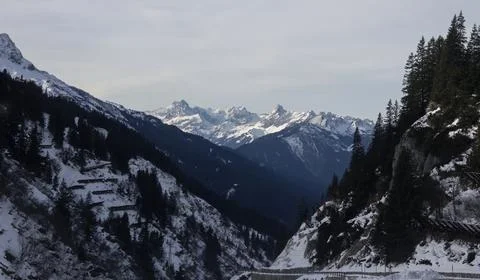 Snow-capped mountains surrounded by rugged terrain in winter landscape Stock Photos